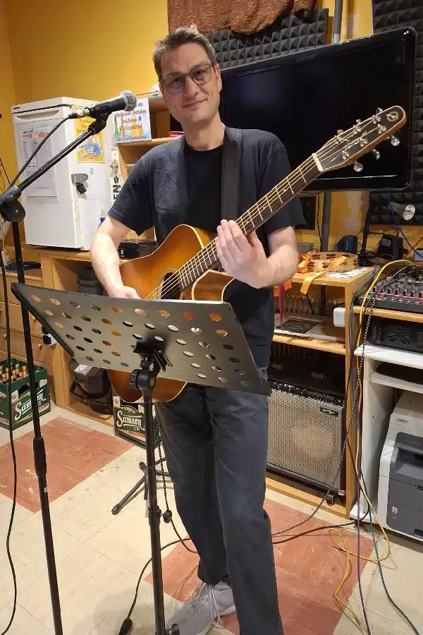 Schlapsi Bernd schlapsi-bernd-sänger-und-gitarrist-mit-gitarre-und-microphon-im-proberaum-2-verein-kreartiv